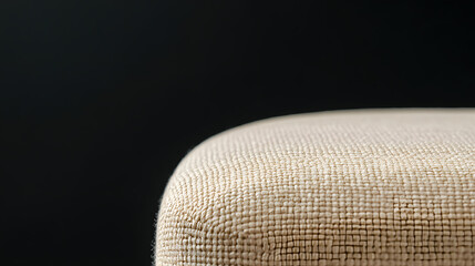 Aufkleber - Close-up of a textured, beige upholstered ottoman with a blurred black background. The tight weave of the fabric and the rounded edge is highlighted.