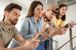 © New Africa - Internet addiction. Group of people with smartphones on stairs indoors