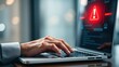 © Chayapus - User's Hand Typing on Laptop with Warning Alert on Screen