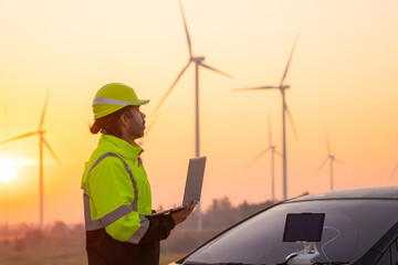 Aufkleber - Engineer working on laptop in front of wind turbines for checking wind turbines of the field during beautiful sunset. Alternative energy concept.