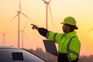 Aufkleber - Engineer working on laptop in front of wind turbines for checking wind turbines of the field during beautiful sunset. Alternative energy concept.