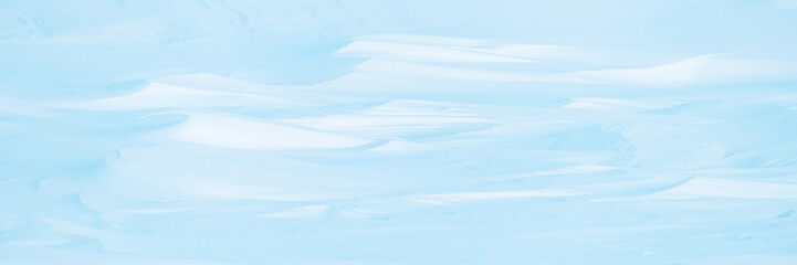 Wall Mural - wide panoramic winter background with snowy ground. natural snow texture. wind sculpted patterns on 