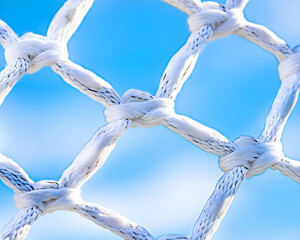 Close-up of knotted white net against blue sky