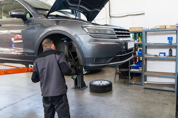 Fototapete - Serviceman checks the brake discs of a car