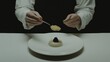 © Phongsri - A chef delicately spooning caviar onto a fine dining appetizer