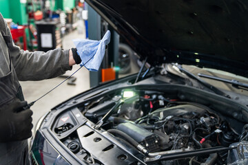 Fototapete - Serviceman checks the oil level in a car engine