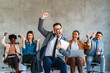 © NDABCREATIVITY - Excited overjoyed diverse business people, team celebrate corporate victory together in office