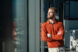 © Westend61 - Young man with beard in a modern office wearing a red sweater and watch