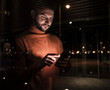 © Westend61 - Man using smart phone seen through glass at night
