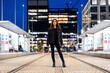 © Westend61 - Young woman standing at a tram stop in the city at night