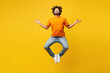 © ViDi Studio - Full body young Indian man wear orange t-shirt casual clothes hold spreading hands in yoga om aum gesture relax meditate try calm down jump high isolated on plain yellow background. Lifestyle concept.