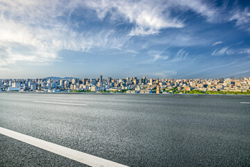 Fototapete - Empty asphalt road with city skyline and blue sky