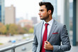 © Minerva Studio - Portrait of businessman adjusting his red tie looking away on office balcony