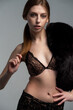 © alipko - Elegant young woman in black lace lingerie with a luxurious fur wrap, posing confidently in a studio setting. Fashionable, sensual, and sophisticated look with soft lighting