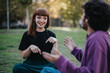 © qunica.com - A young couple engages in a lively and joyful conversation in a sunny outdoor park setting, capturing a moment of friendship and connection.
