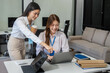 © NINENII - Business woman sitting on desk using Tablet and laptop. Portrait of busy secretary in working environment. Happy young businesswoman in casual working on computer in office.