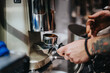 © qunica.com - A barista uses a professional coffee grinder to prepare ground espresso in a portafilter. Capturing the art of crafting coffee in a contemporary cafe setting with attention to detail.