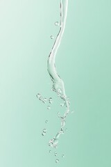 Poster - Droplets of water swirl and fall against a soft green background, creating a sense of fluid motion that evokes calm and purity in the composition