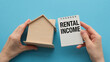 © Pawel - A person holding a house and a notebook with the word Rental Income written