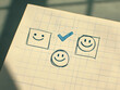 © Pukan - A notepad shows three smiley face sketches, with one checked, symbolizing a choice or preference in a cheerful manner.