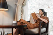 © SHOTPRIME STUDIO - Relaxed woman in brown outfit enjoying a book indoors with a cozy atmosphere and warm lighting, showcasing a peaceful moment and stylish interior design