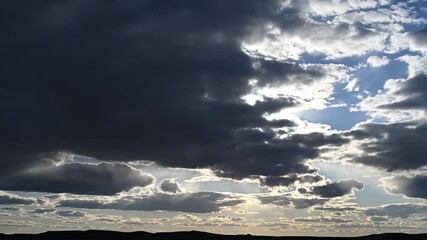 Wall Mural - Time lapse of high contrast summer clouds and sun above a hilly western landscape
