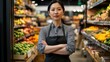 © jannik27s - an attractive, smiling female supermarket manager standing in front of the fruit and vegetable area