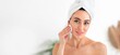 © Prostock-studio - A woman with a towel on her head applies skincare during a pampering session at home. Her gentle face massage promotes relaxation and enhances her skin's youthful appearance, copy space
