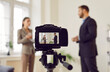 © Studio Romantic - Close up view of a video camera recording an interview or hosting a live broadcast. The scene captures the interaction between a reporter and a guest, part of a TV show, news program or PR company.