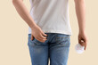 © Pixel-Shot - Young man with sad smile on beige background, back view. Hemorrhoids concept