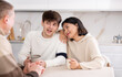 © JackF - Couple of young woman and young guy and adult man talking while sitting at table in kitchen