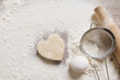 © st.kolesnikov - Heart-shaped cookie dough on floured surface with egg, rolling pin, and sieve — homemade baking for Valentine's Day or festive culinary concept.