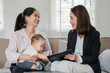 © Satori Studio - Businesswoman consulting with a mother and baby in a cozy living room, showcasing work-life balance and professional advice.