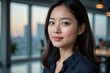 © MT - Portrait of a Young East Asian Woman in a Modern Office Setting at Dusk, Showcasing Her Professional Attire and Confident Expression Against a City Skyline Backdrop