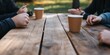 © Armin - An inviting setup of hands around coffee cups on a rustic wooden table, encapsulating social bonding, warmth, and the joy of shared moments in relaxation.
