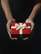 © nelzajamal - A woman's hands holding a red gift box with a white bow  - ai