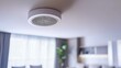 © Muhammad - A photo of an indoor smoke detector with a circular design and white color, hanging on the ceiling in a living room.