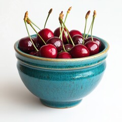 Aufkleber - Fresh cherries overflowing in a vibrant blue ceramic bowl on a white table