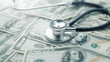 © pattozher - Healthcare Costs: A stethoscope rests atop a chaotic pile of hundred-dollar bills, symbolizing the financial burden associated with healthcare expenses.