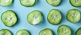 Sliced cucumber pieces arranged on a colorful background. Top down aerial view of sliced fresh vegetable with juice textured. Flat lay composition with copy space for food and health design. AIG55.