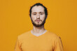 © SHOTPRIME STUDIO - Young confident man with curly hair wearing a yellow shirt, standing against a vibrant orange background, exuding self assuredness and positivity