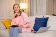 © zinkevych - Dreamy positive woman sitting on a sofa at home and writing something