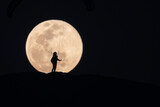 Sylwetka paralotniarza na tle pełni księżyca – nocna fotografia
