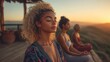 © SimpleDesignStudio - Three Diverse Women Practicing Mindfulness Meditation at Sunset on a Scenic Outdoor Deck Overlooking Lush Green Hills, Promoting Peace and Serenity