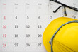 © pla2na - Flat lay of safety glass and yellow worker helmet on blank white calendar background copy space. Payday, working or training schedule for worker or employee, labor day, holiday and so on concept.