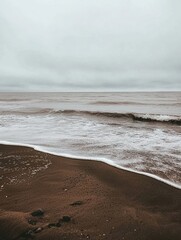 Fototapete - Lonely seashore with gentle waves under overcast sky inviting reflection and serenity Generative AI