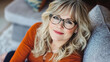 © MashMash - Confident middle-aged blonde woman with glasses smiling in a modern home interior, natural lighting, warm atmosphere, professional portrait for business, lifestyle, and personal branding