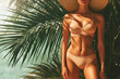 © Vovmar - A slender girl shows off her bikini under huge palm leaves. Generated by artificial intelligence