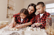 © st.kolesnikov - Happy mother and children baking together, family fun in the kitchen, messy hands, playful bonding, homemade cooking, joyful childhood moments.