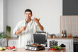 © Pixel-Shot - Young man cooking tasty sausages and vegetables on modern electric grill at table in kitchen